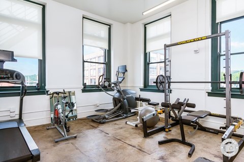 A well equipped gym with treadmill, weights and other equipment.